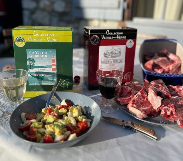 table printanière avec une salade composé et des grillades, un bag-in-box de vin blanc et un autre de vin rouge