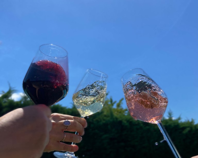 verres de vins levés vers le ciel bleu avec un grand soleil